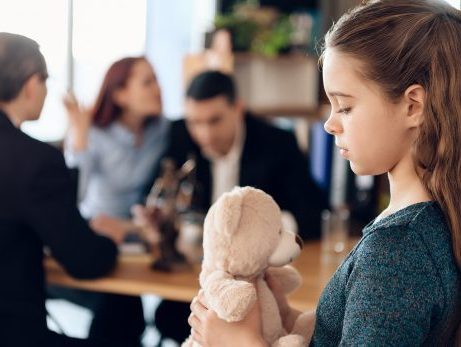 child holding teddy bear looking sad